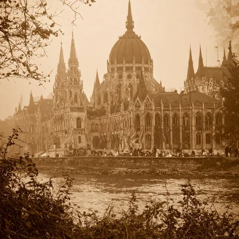 Parliament Observation: A spired parliament building across a river, in sepia.